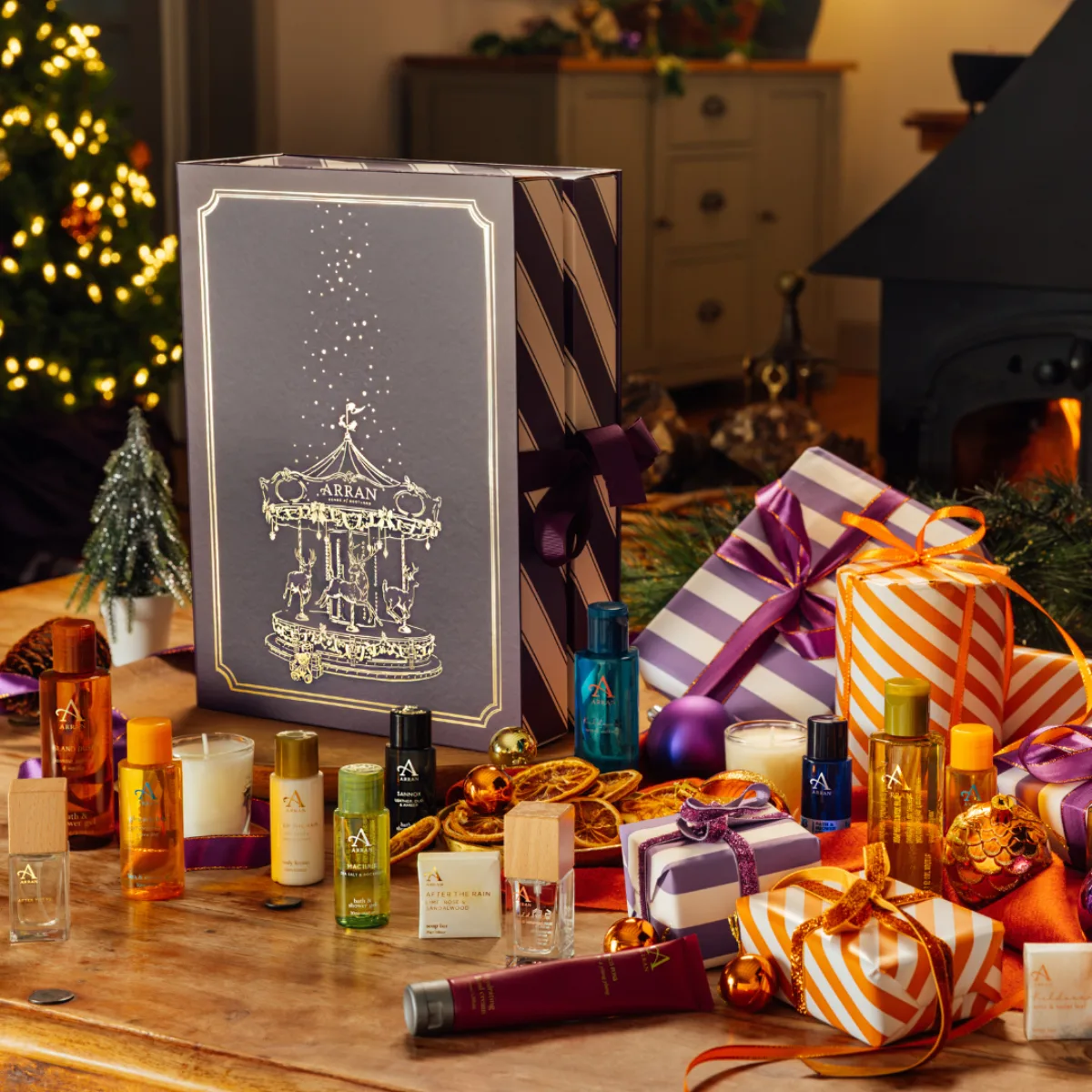 The ARRAN Sense of Scotland advent calendar, a purple and gold carousel-illustrated box, surrounded by its contents: bath and shower gels, body oils, a candle, soap and small fragrance bottles