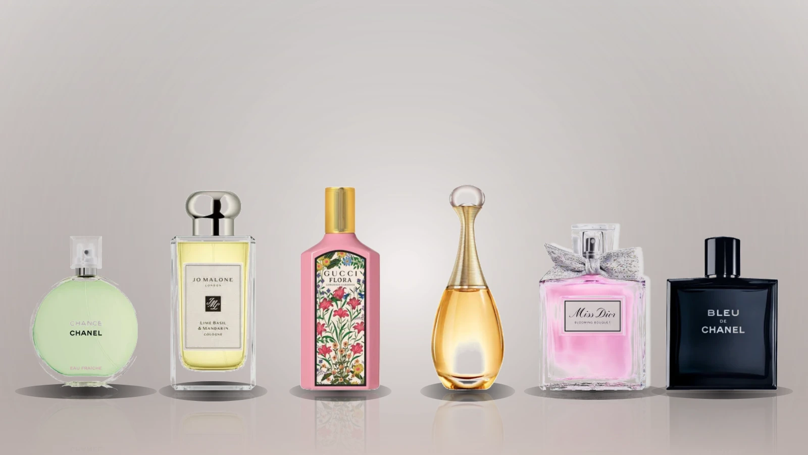 Five perfume bottles are arranged on a sunlit surface with lemons, driftwood, and a pool in the background